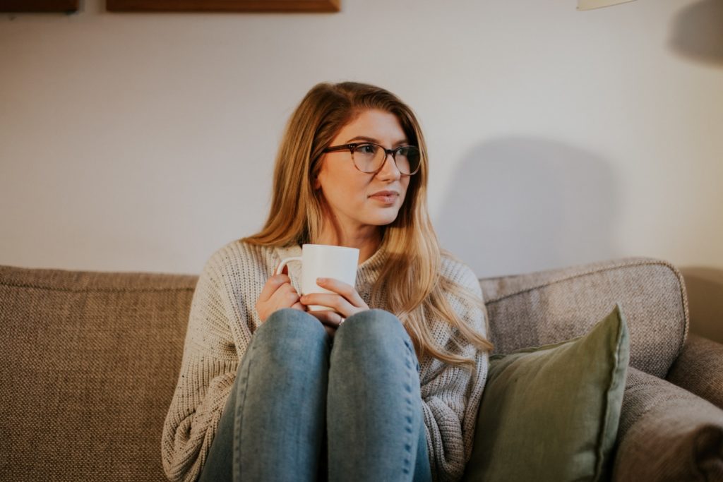 woman sitting on sofa thinking about her reasons for trying a relationship for the third time
